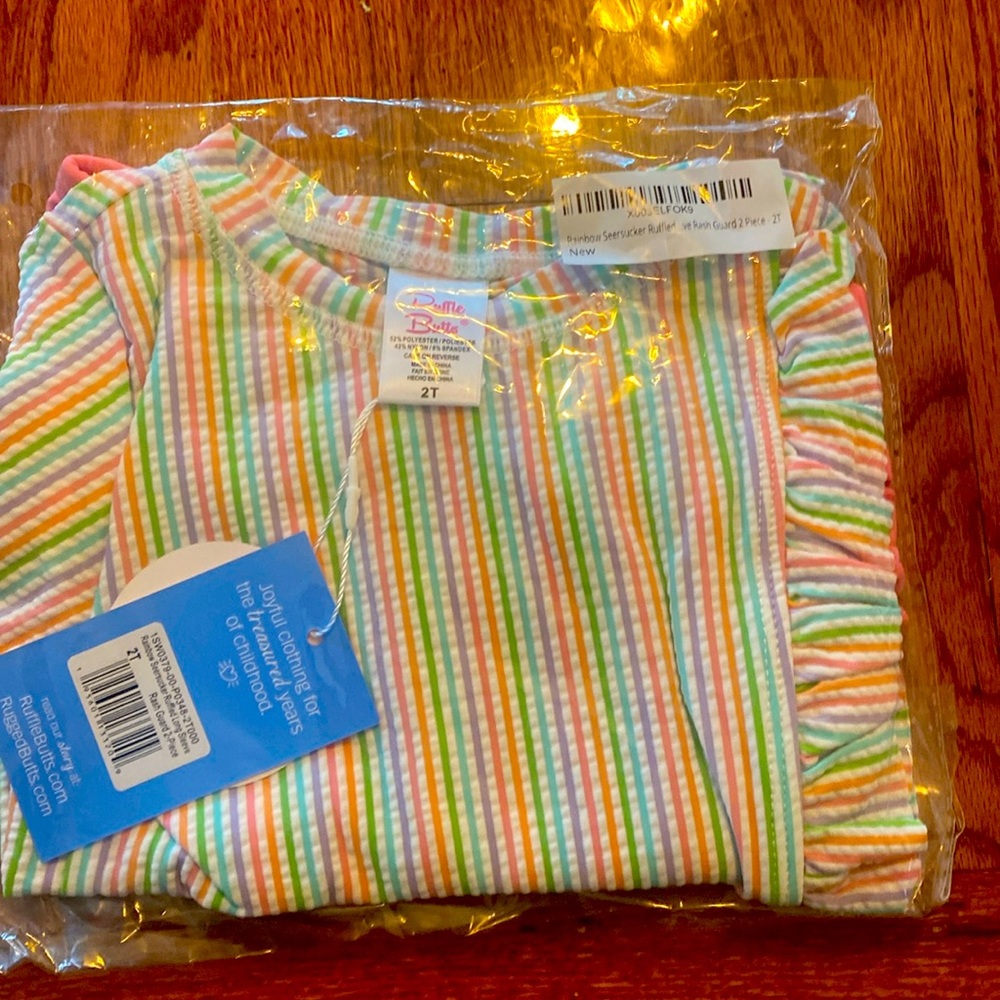 NWT two piece. Light pastel rainbow print top with pink ruffle butt bottoms.
